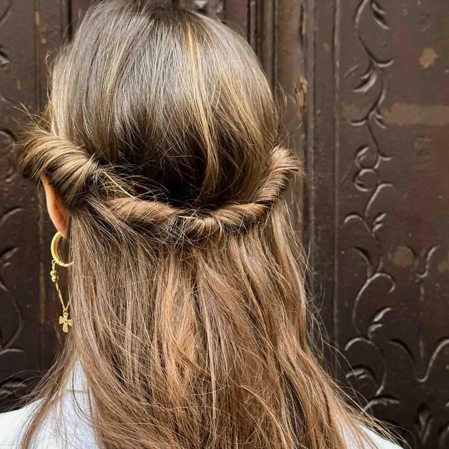 Pequeño peinado trenzado en cabello castaño con detalles dorados, ideal para ocasiones elegantes.