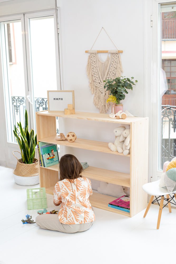 Estantería de madera clara, estilo escandinavo, con tres estantes y decoración minimalista en un ambiente luminoso.