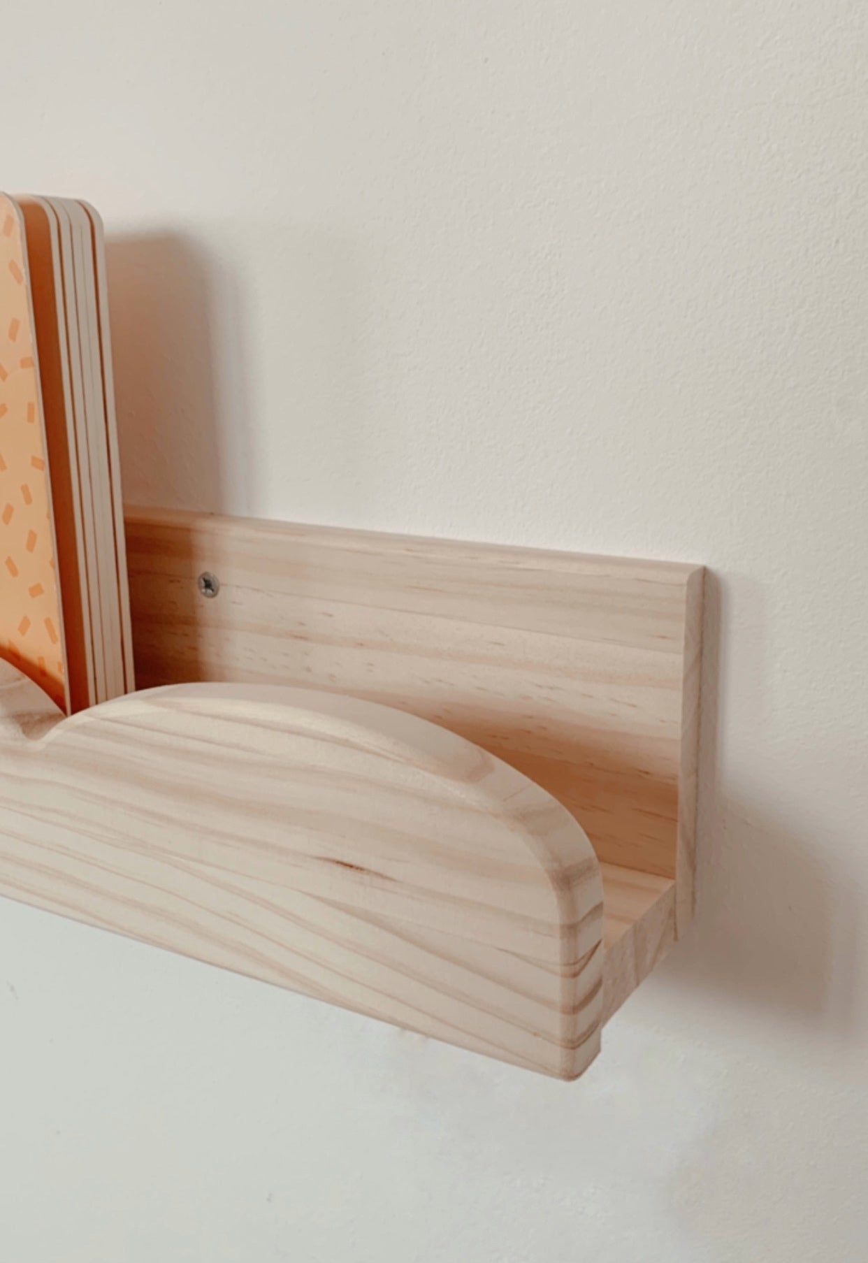 Estante de madera clara con diseño curvo, ideal para organizar libros o revistas en casa.