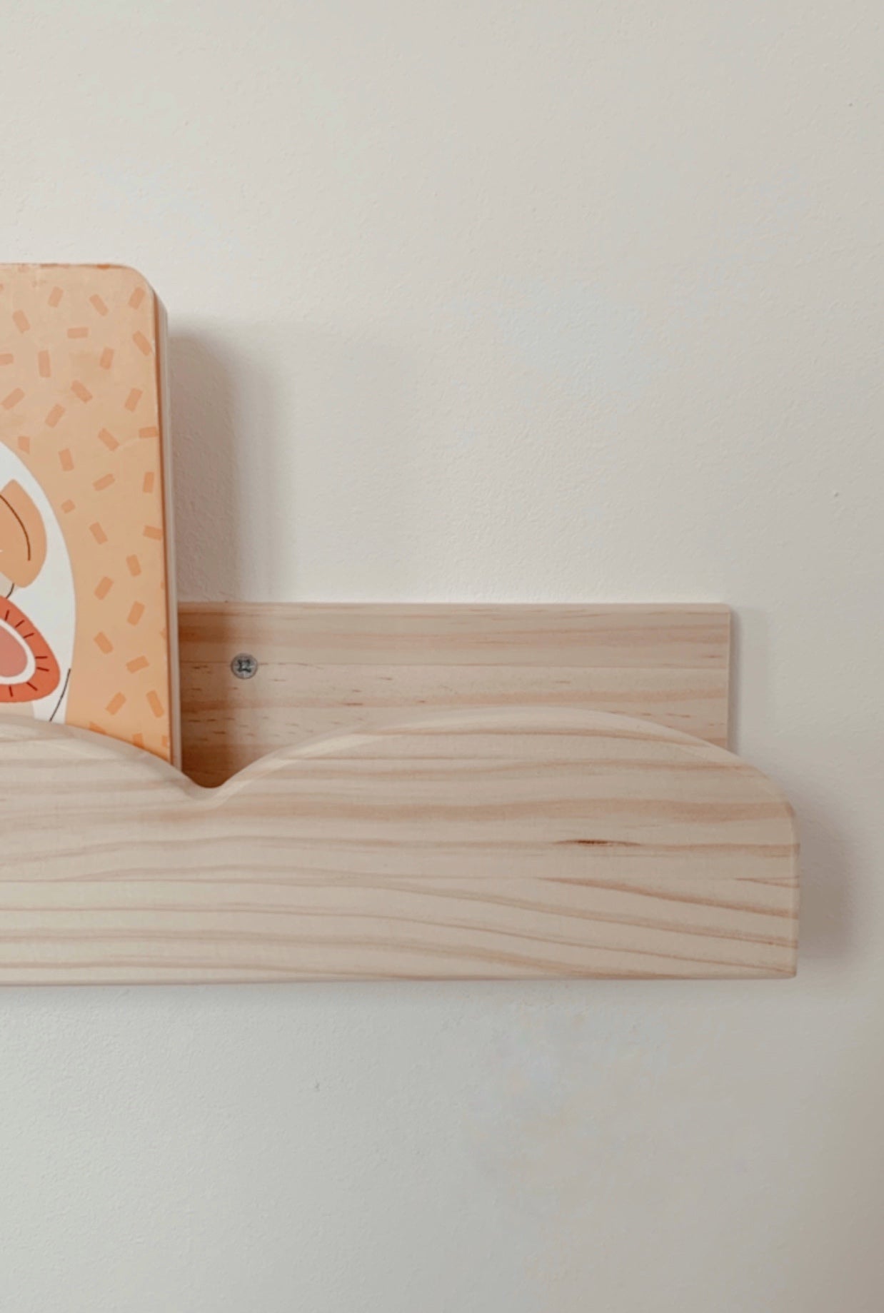 Estante de madera clara con diseño curvo para libros infantiles, ideal para decoración y organización.