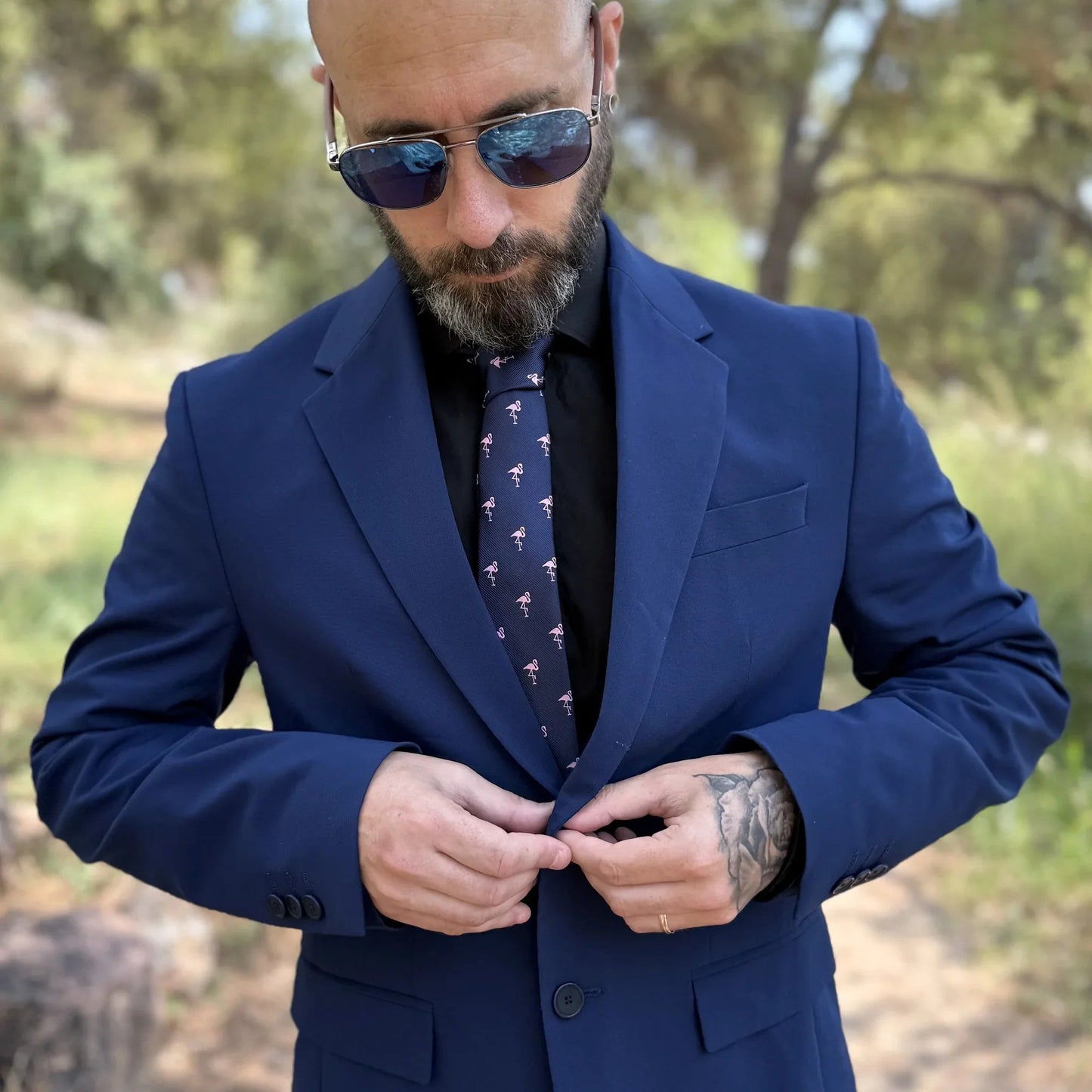vista frontal en detalle de modelo masculino con gafas y traje con corbata azul diseño flamencos