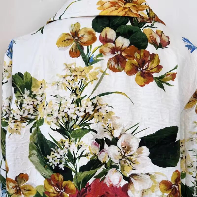White long brocade jacket featuring a vibrant, multicolored floral print with yellow, white, and green blossoms.