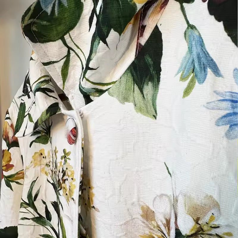 White brocade long jacket featuring a vibrant, multicolored floral print with a classic collar and button closure.