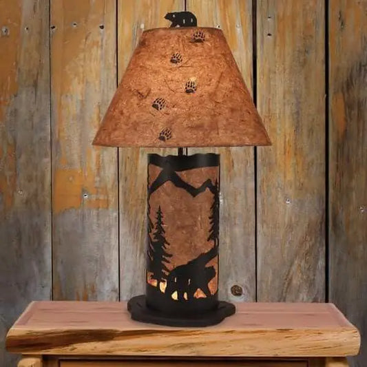 Rustic table lamp with a mountain and bear silhouette base and a paper shade featuring bear paw prints.