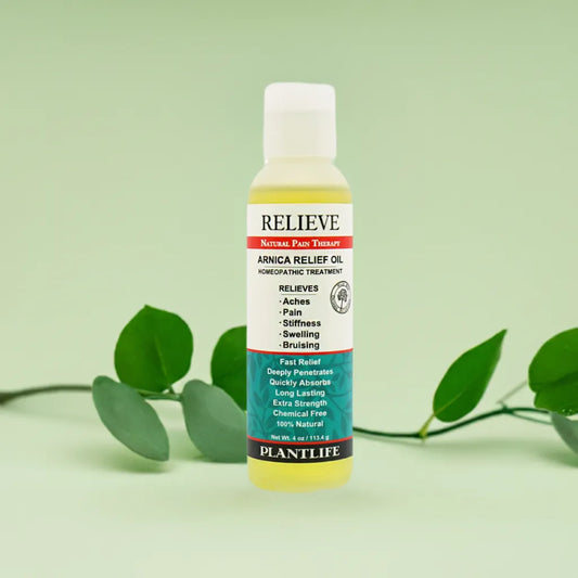 A bottle of Plantlife Arnica Relieve Oil on a light green background with green leaves.