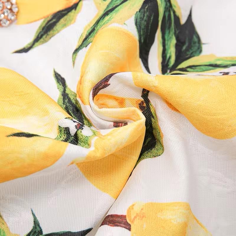 White floral fabric with vibrant yellow lemons, soft texture, perfect for summer clothing and accessories.