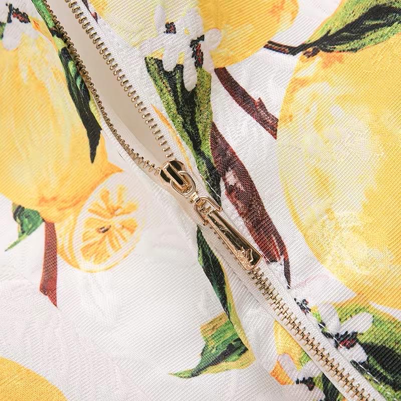 Yellow lemon print fabric with floral accents and a gold zipper detail. Ideal for summer fashion.