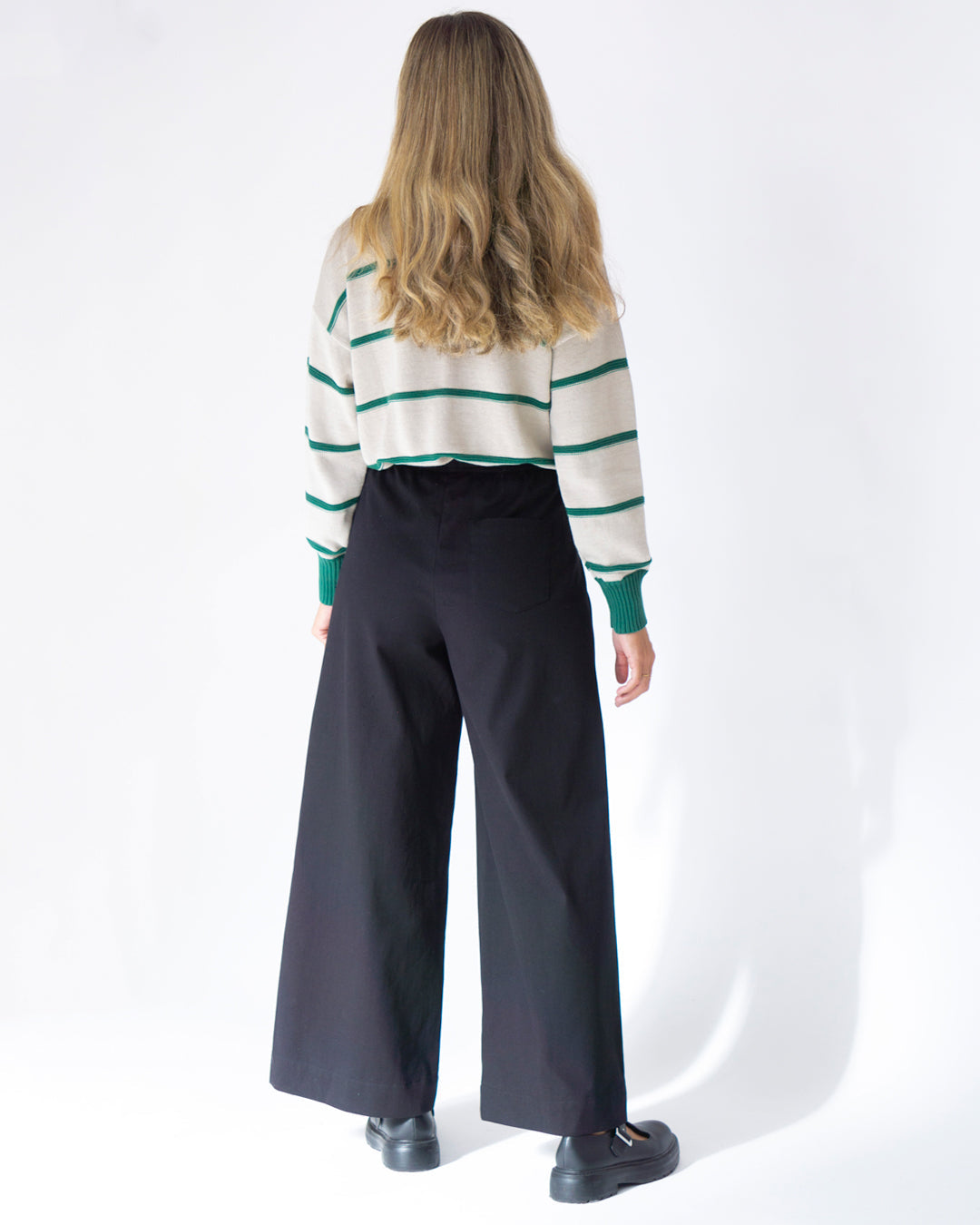 Suéter a rayas crema y verde con pantalones anchos negros, elegante y moderno para un look casual.