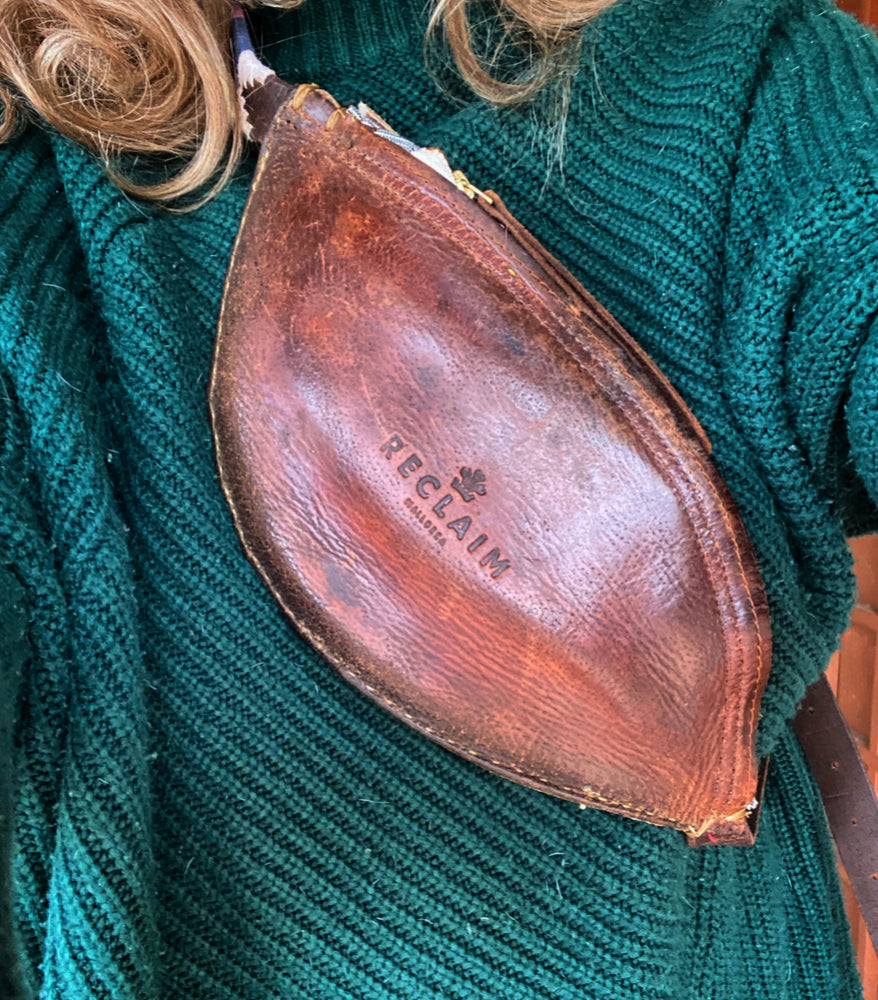 Bolso Riñonera Campos Vintage Roja sobre una chaqueta verde, hecho de cuero reciclado con detalles únicos.