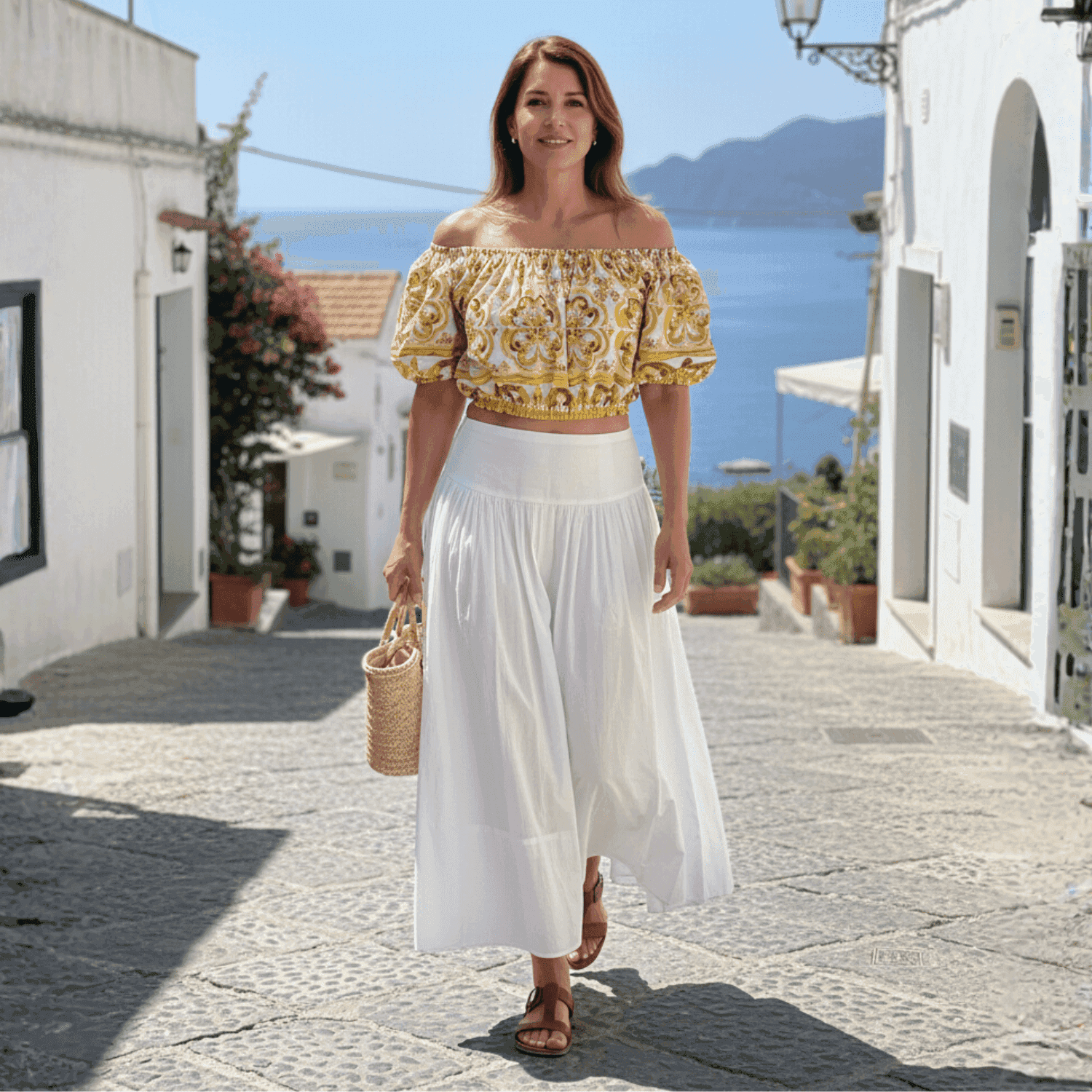 Off-the-shoulder cotton crop top with yellow and white Mediterranean majolica tile print, worn with a white maxi skirt.