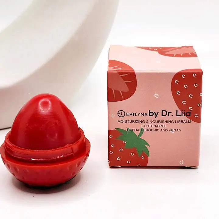 Egg-shaped red lip butter next to a strawberry-patterned square box labeled EpiLynx by Dr. Liia on a white surface.