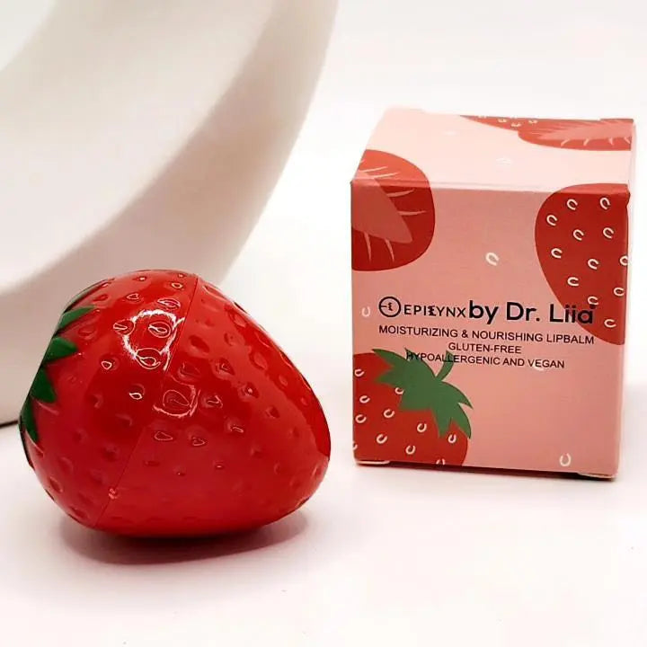 Strawberry-shaped red lip balm container next to a matching pink cardboard box with strawberry graphics and text.