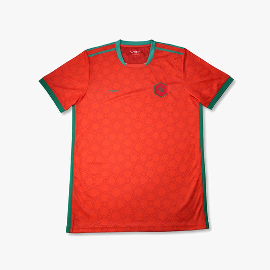 Maillot de sport rouge VO7 à motifs géométriques, col et bords verts, avec écusson en forme d'hexagone sur la poitrine.