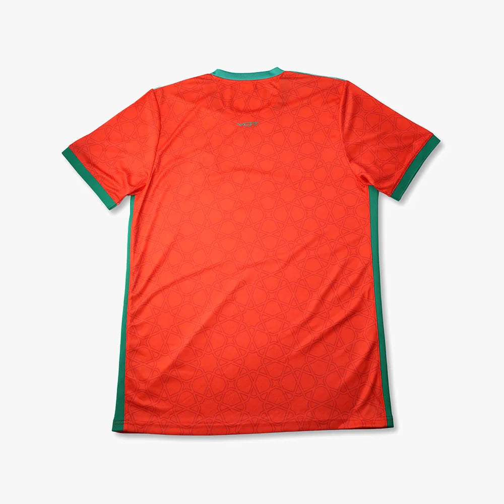 Maillot VO7 rouge à motifs géométriques, col et bords de manches verts, style sportif en tissu technique léger.
