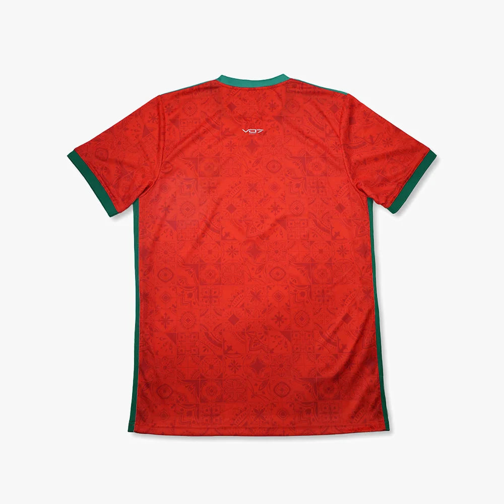 Maillot VO7 rouge à motifs géométriques ton sur ton, col et bords de manches verts, logo VO7 au dos. Coupe droite.