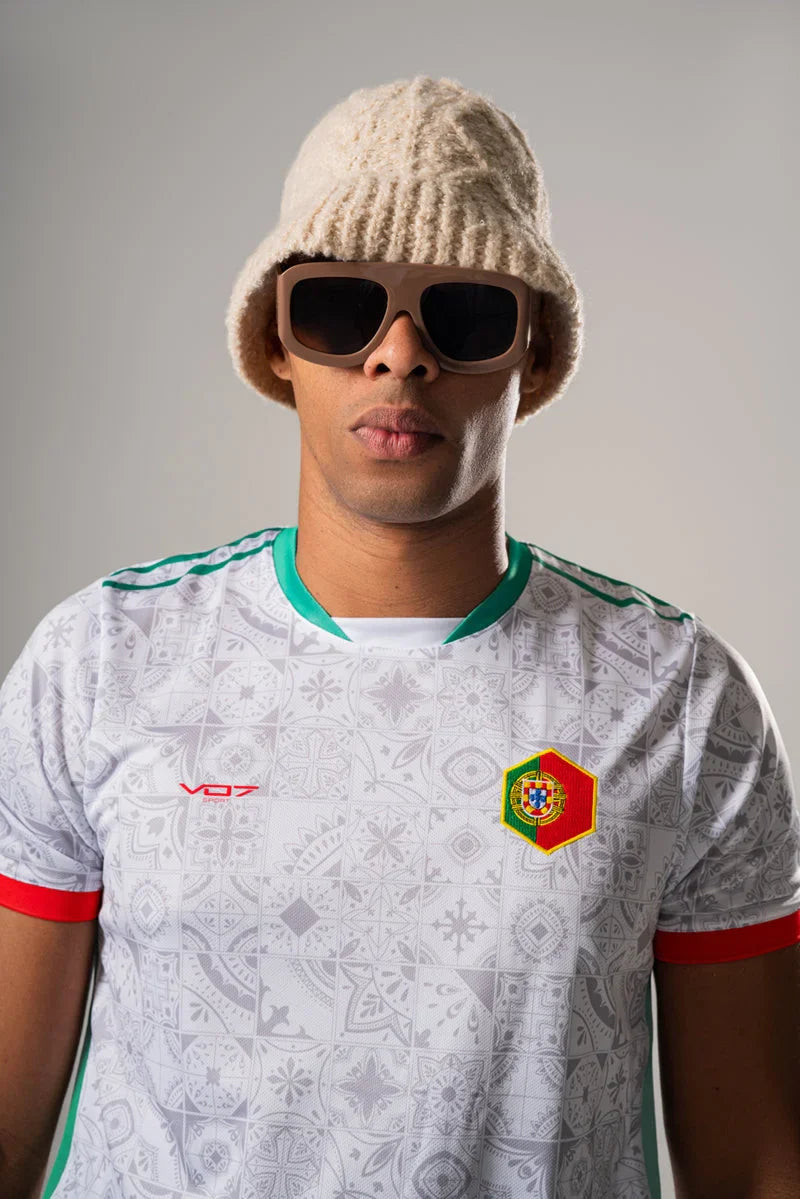 Maillot blanc VO7 à motifs tuiles, col vert, bords de manches rouges et écusson hexagonal du Portugal sur la poitrine.