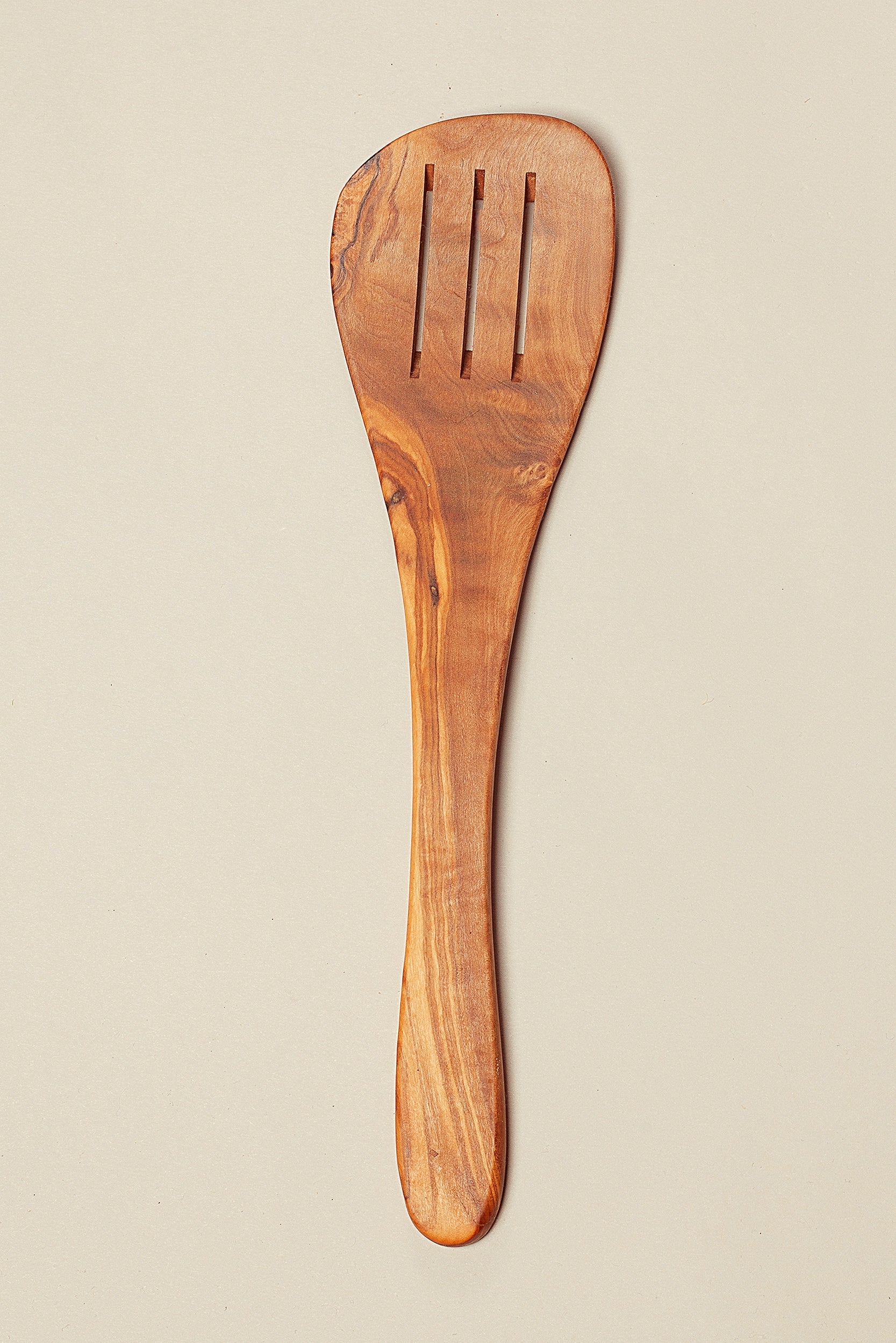 Espátula de madera de olivo, color marrón, con tres ranuras, ideal para cocina gourmet y utensilios de cocina.
