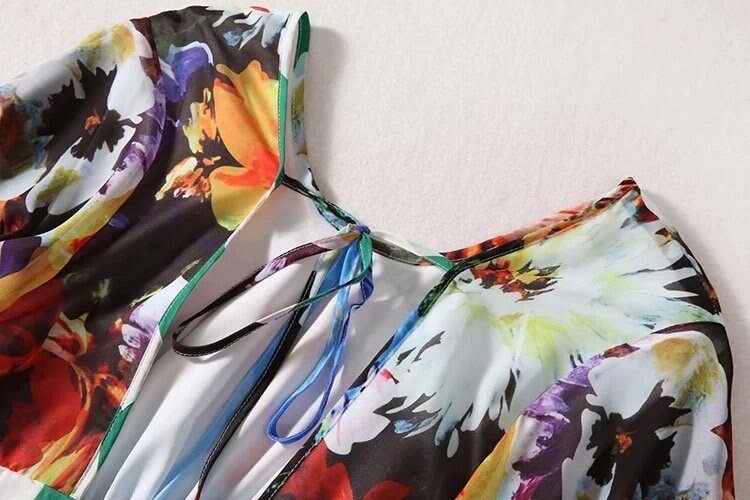 Colorful floral-print blouse with a V-neck and tied detail, made from lightweight, flowy fabric. Perfect for summer.