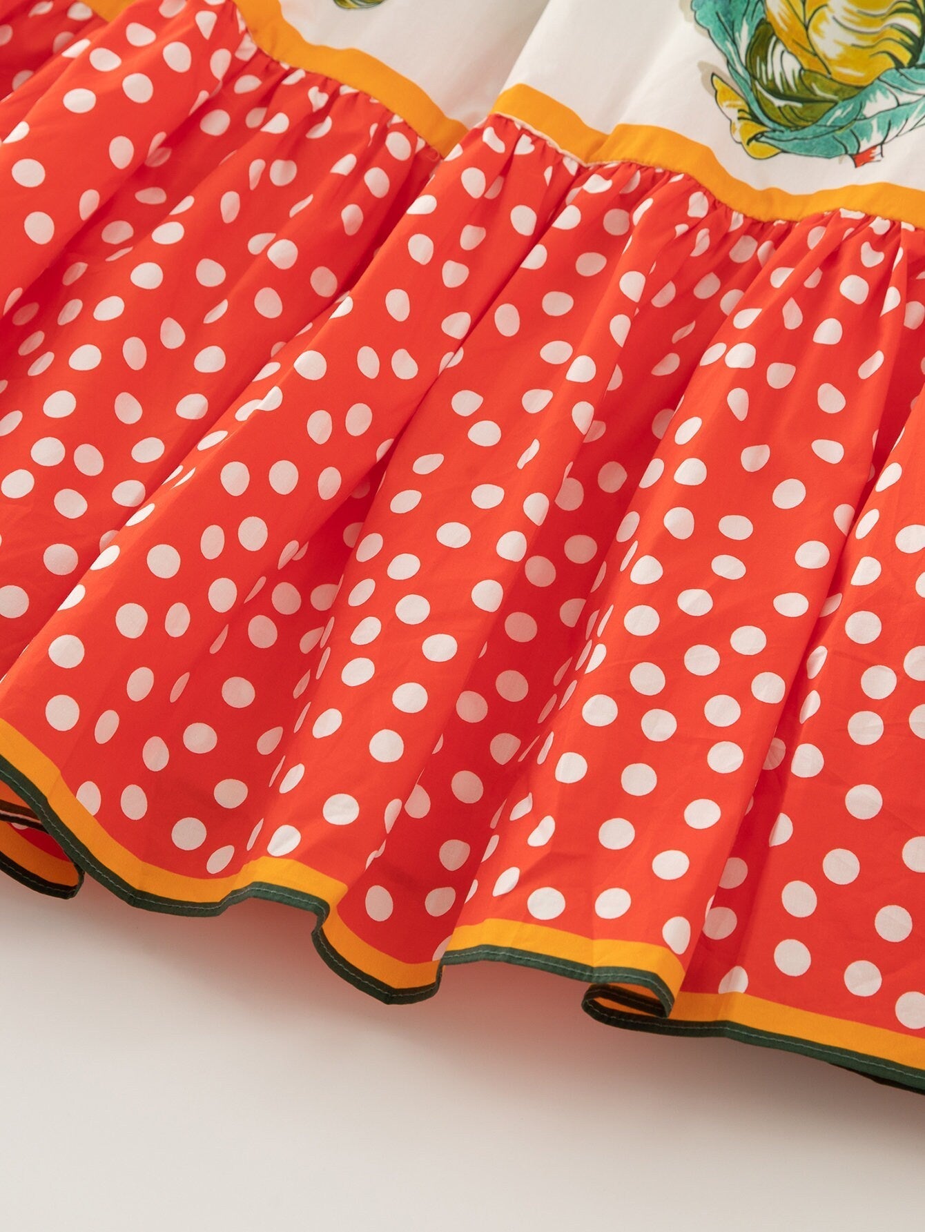 Red polka dot skirt with floral print detail, made from lightweight cotton, perfect for casual summer wear.
