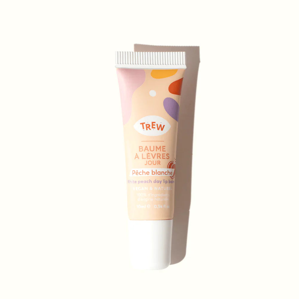 White peach lip balm tube with a cream base, playful colorful abstract shapes, and white cap on a white background.