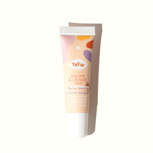 White peach lip balm tube with a cream base, playful colorful abstract shapes, and white cap on a white background.