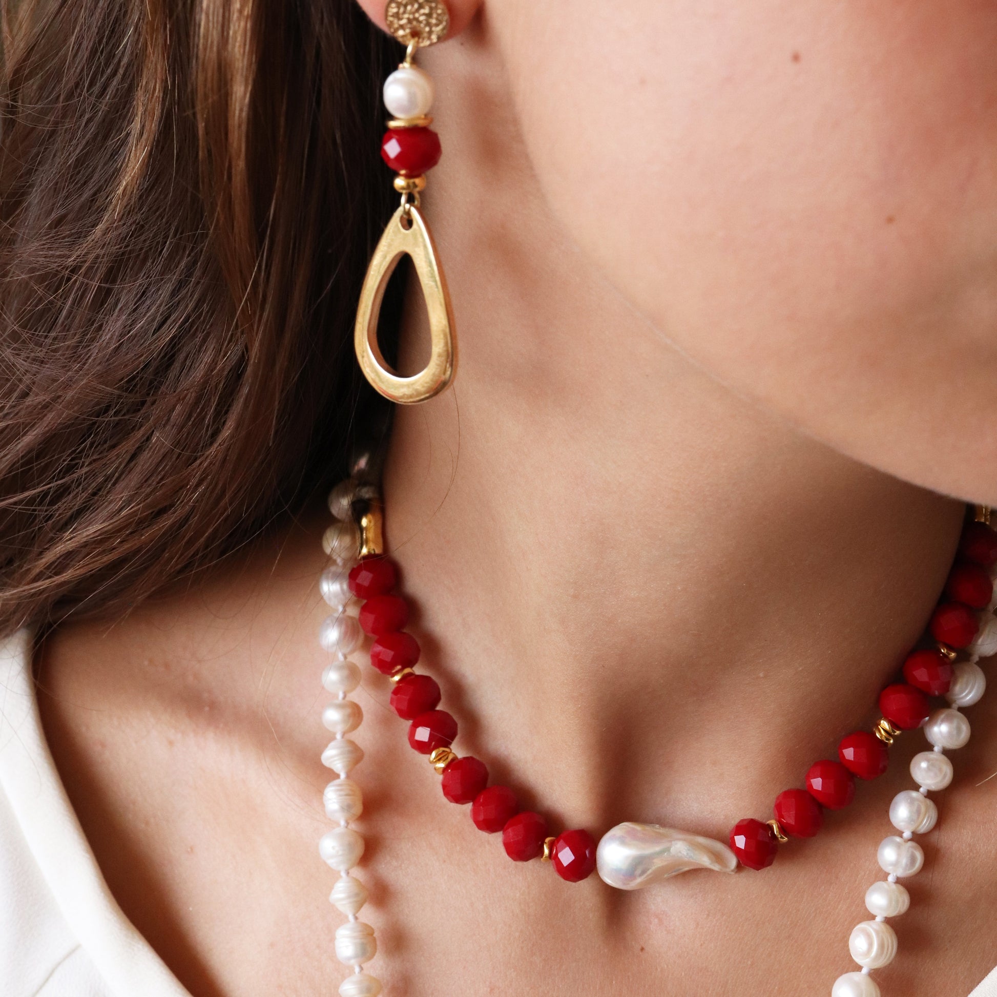 Collar de perlas y cuentas rojas con aretes dorados, estilo bohemio y elegante.