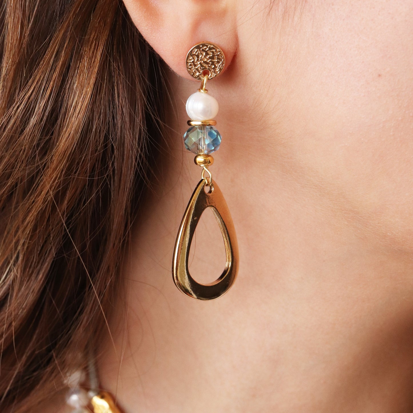 Pendientes dorados con perla y cristal azul, diseño elegante y moderno en forma de gota.
