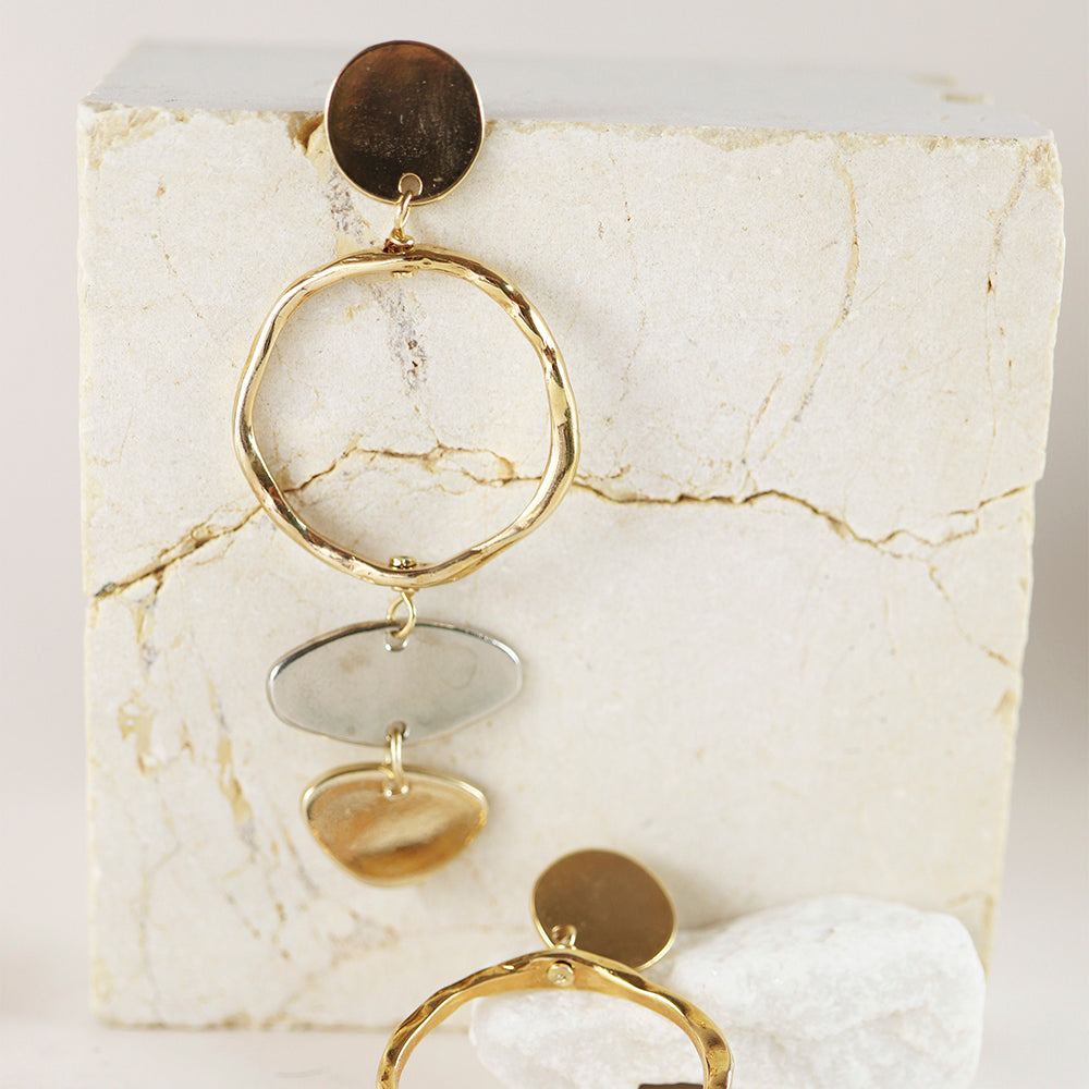Pendientes de metal dorado con diseño moderno, círculos texturizados y formas geométricas en tonos plateados y dorados.