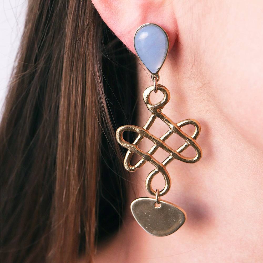 Aretes largos dorados con forma entrelazada y detalle en lágrima azul claro.