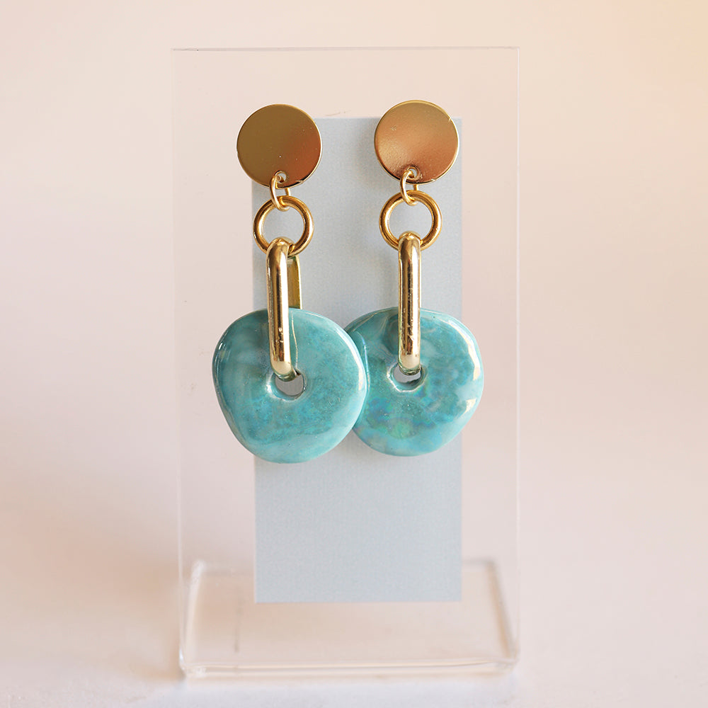 Pendientes de cerámica azul brillante con detalles dorados, estilo moderno y elegante.