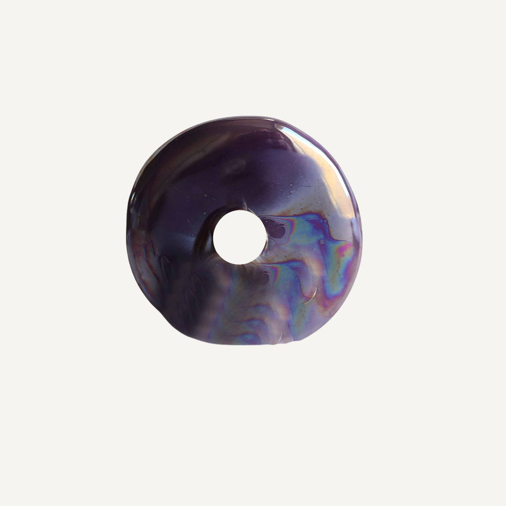Donut de resina morado con destellos iridiscentes, diseño moderno y elegante, ideal para decoración o joyería.