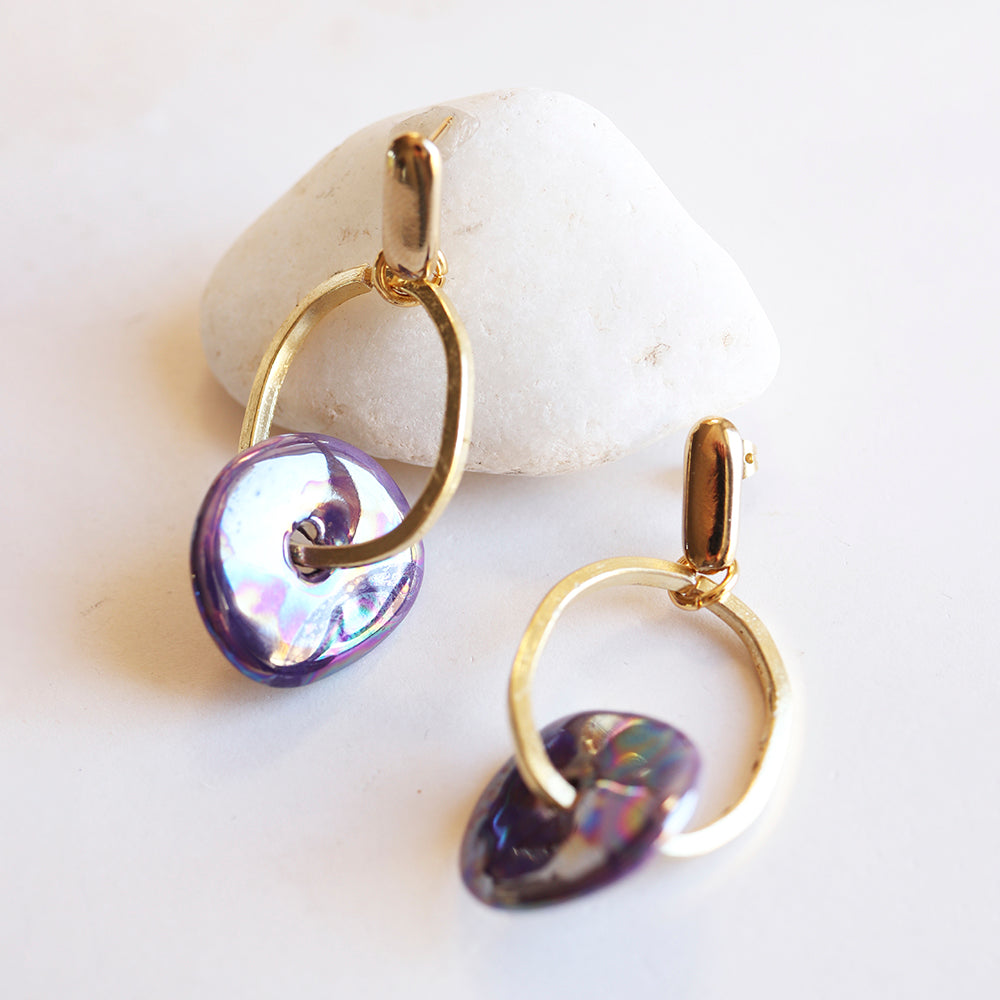 Pendientes de aro dorados con detalles en nácar púrpura y azul, estilo moderno y elegante.