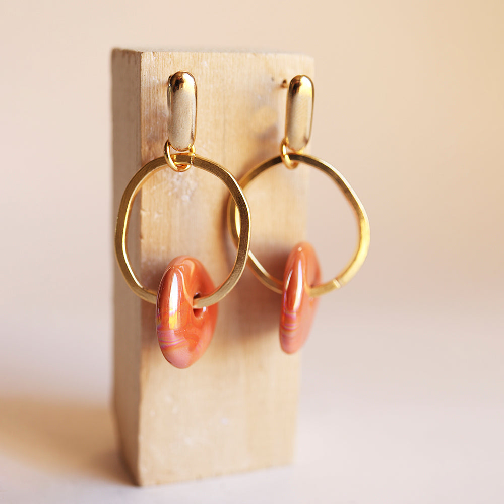 Pendientes de aro en oro con detalle de resina naranja, estilo moderno y elegante.