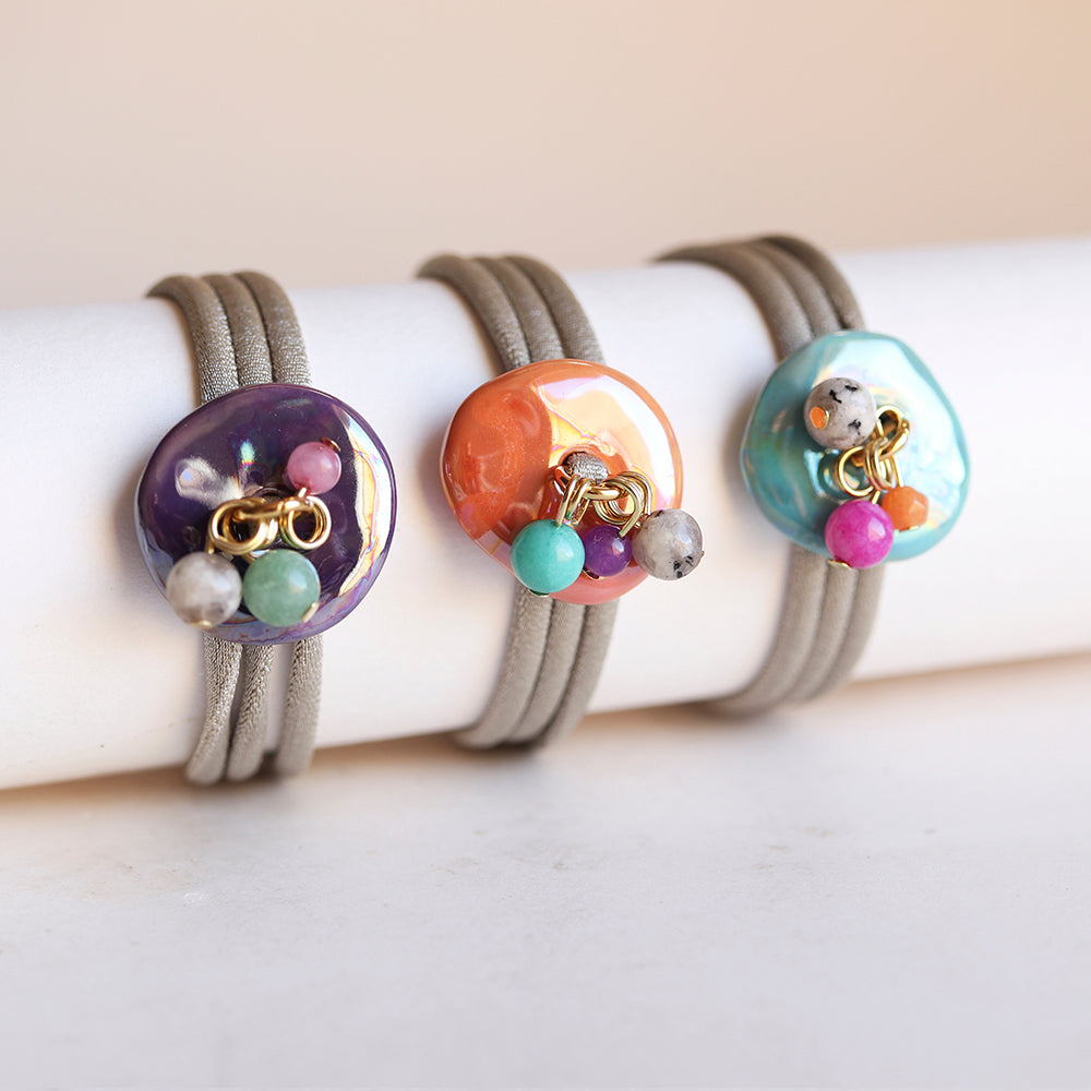 Pulseras de goma con charm colorido en púrpura, naranja y turquesa, estilo moderno y vibrante.