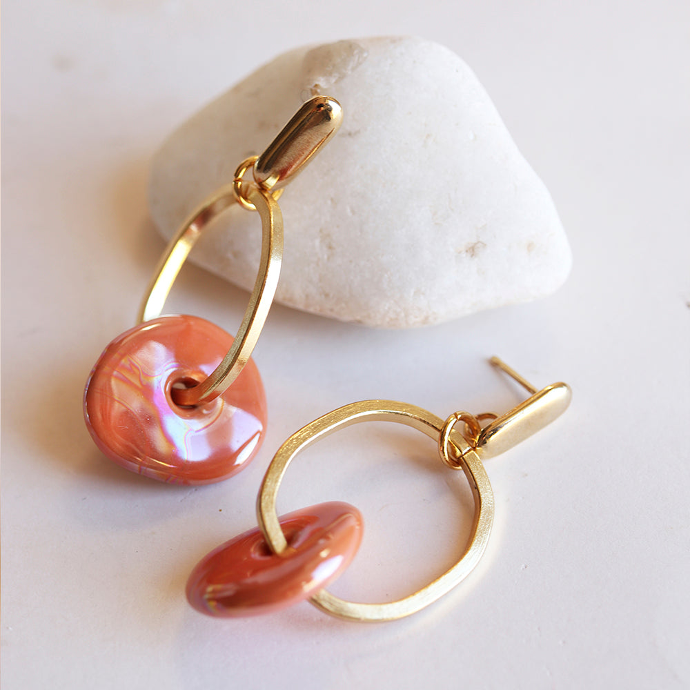 Pendientes de oro con cuentas de concha rosa y diseño moderno, perfectos para un look elegante y vibrante.