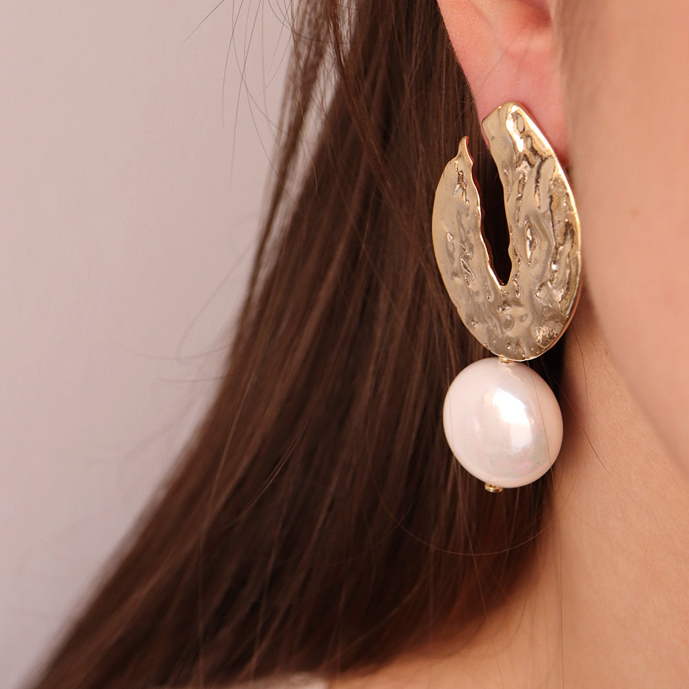 Pendientes dorados con textura y perla blanca, estilo moderno y elegante, ideales para cualquier ocasión.