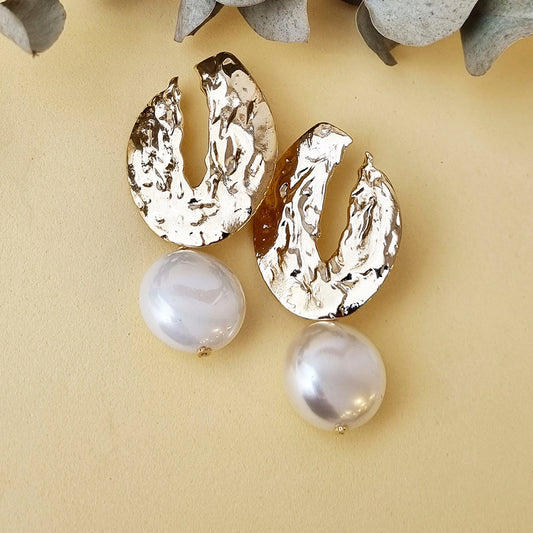 Pendientes de metal dorado con forma artística y perlas blancas, perfectos para ocasiones elegantes.
