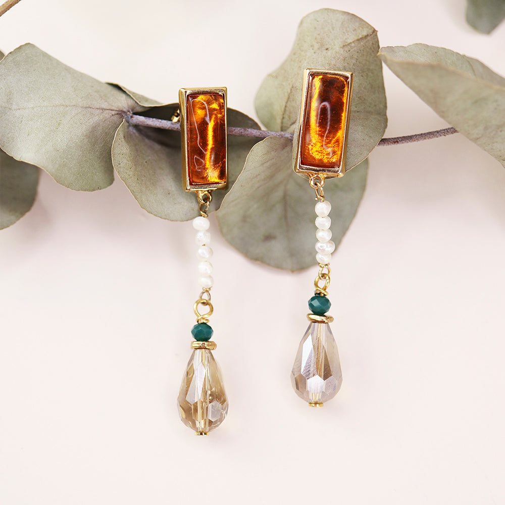 Pendientes elegantes con ámbar y perlas, acabados en dorado, con detalles en verde y cristal, estilo bohemio.