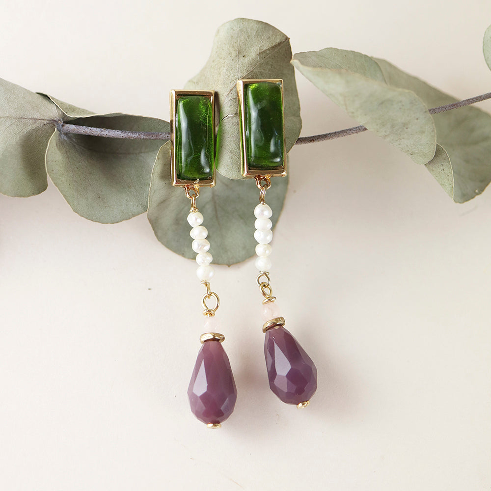 Pendientes de botón verdes con perlas blancas y gotas moradas, estilo elegante y sofisticado.