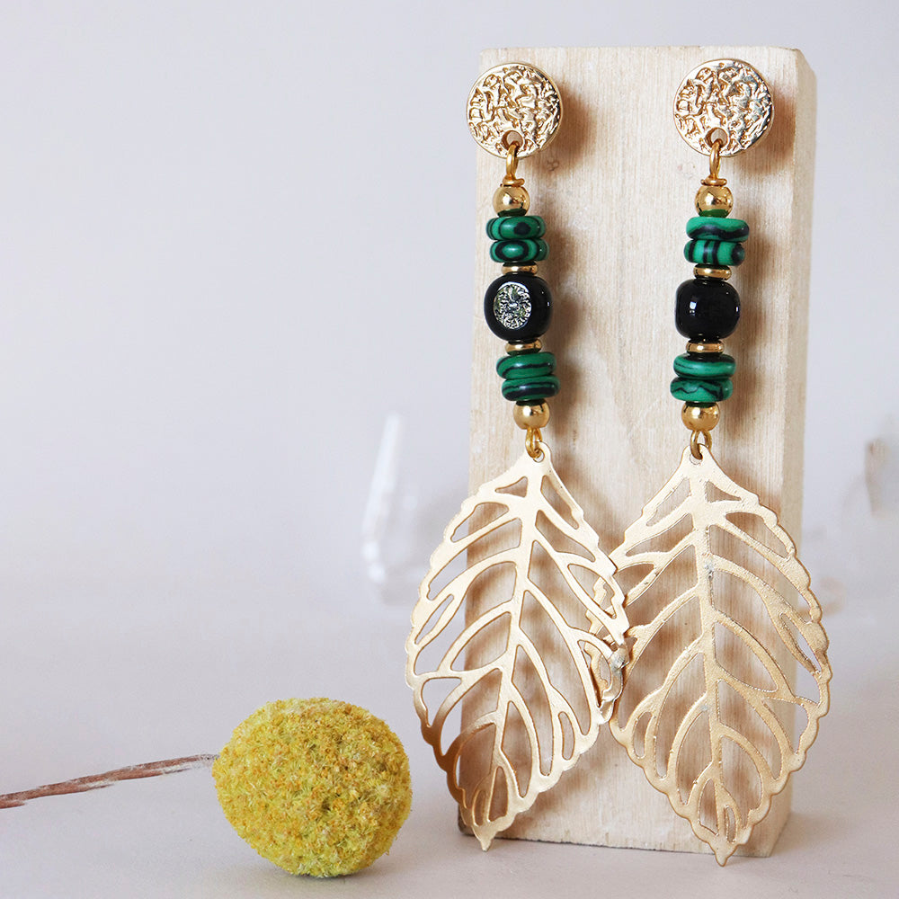 Pendientes largos de metal dorado con hojas, cuentas negras y verdes, estilo bohemio y moderno.
