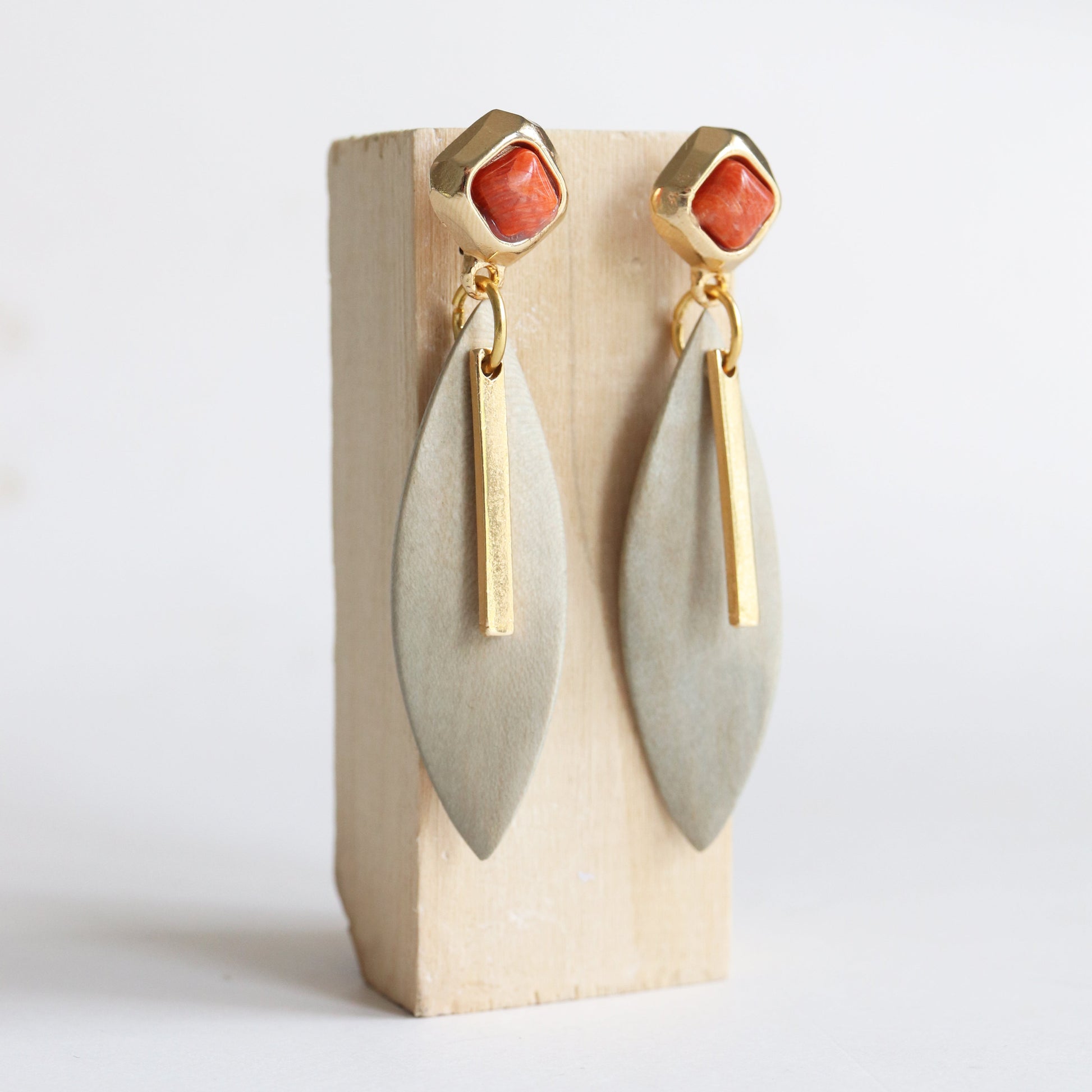 Pendientes de metal dorado con piedra coral y forma de hoja en color gris. Elegantes y modernos para cualquier ocasión.