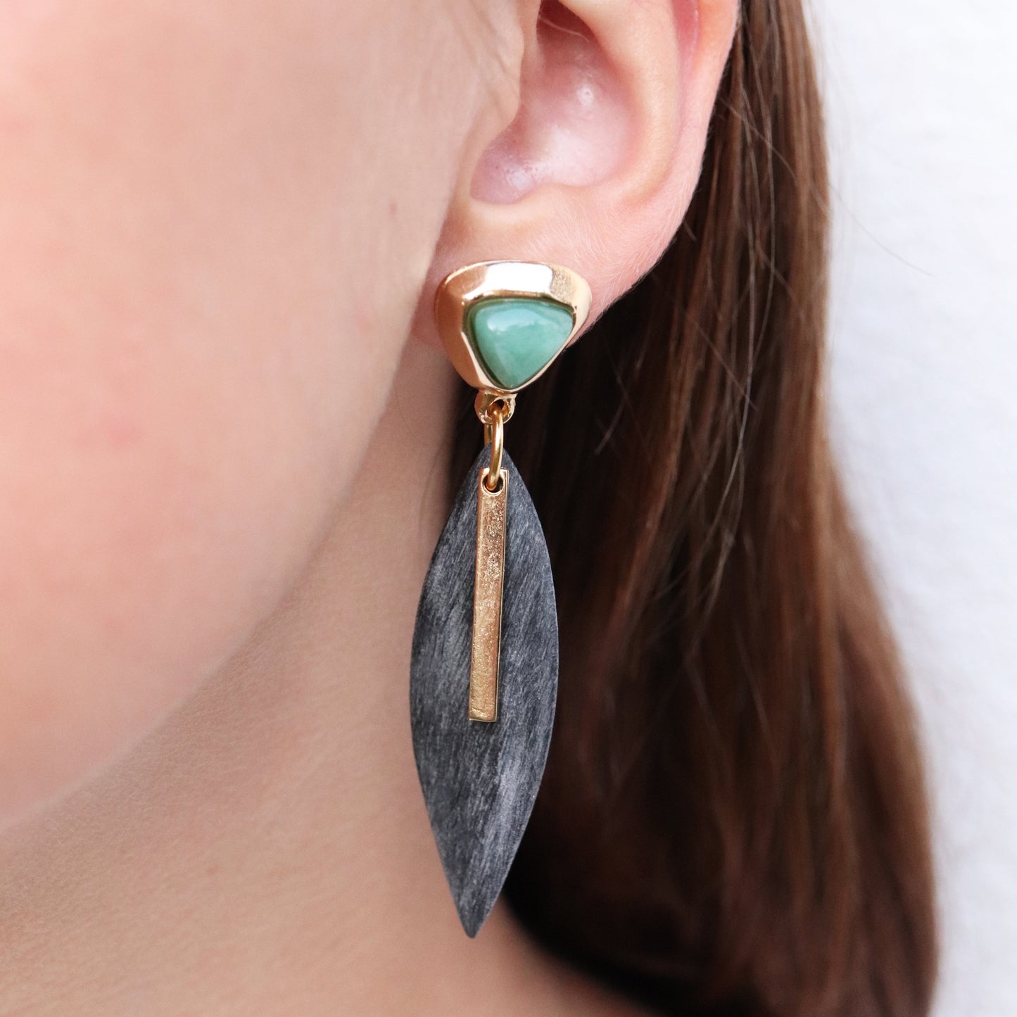 Pendientes de hojas en dorado y negro con piedra verde, estilo moderno y elegante para ocasiones especiales.