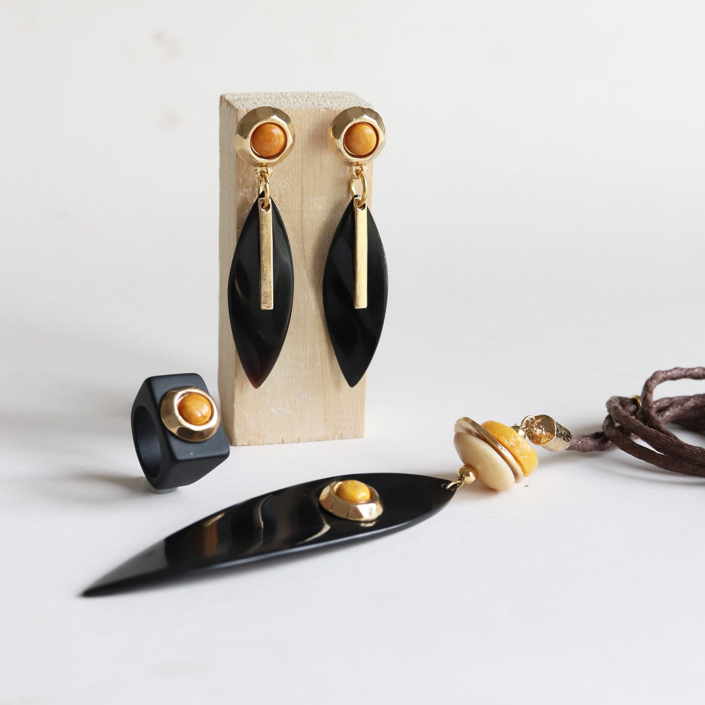 Pendientes negros de resina con detalles dorados y anillo a juego, estilo moderno y elegante.