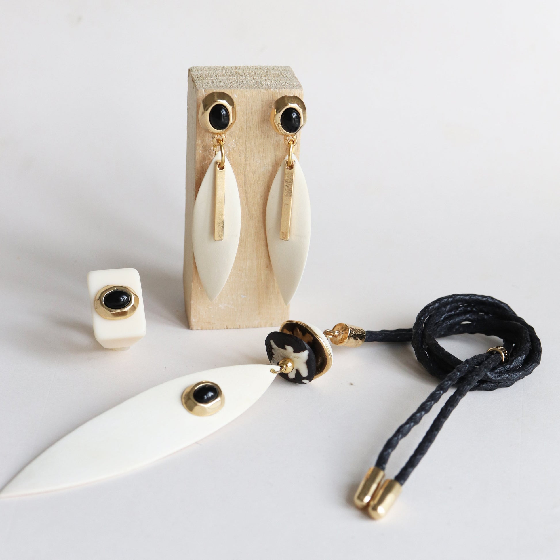 Pendientes dorados con ónice negro y colgante de hueso, estilo moderno y elegante. Ideal para ocasiones especiales.