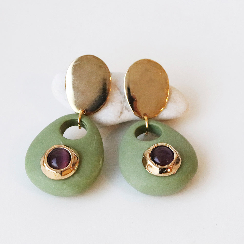 Pendientes de cerámica verde con detalles dorados y piedra morada, estilo moderno y elegante.