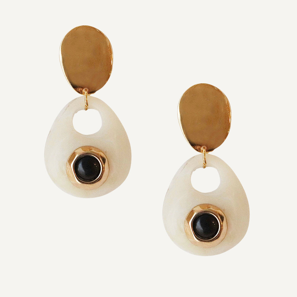 Pendientes de gota en color marfil con detalle dorado y piedra negra, estilo moderno y elegante.