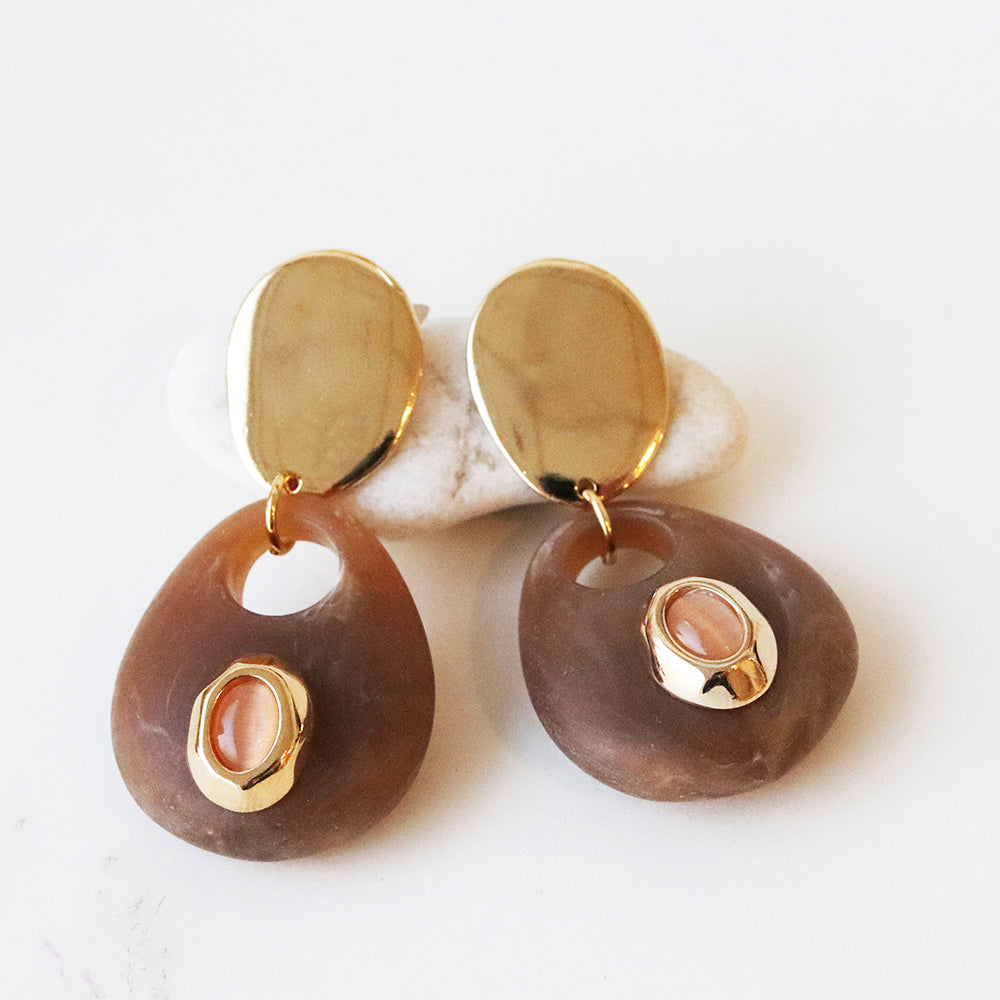 Pendientes de resina marrón con detalles dorados y piedra rosa, estilo moderno y elegante.