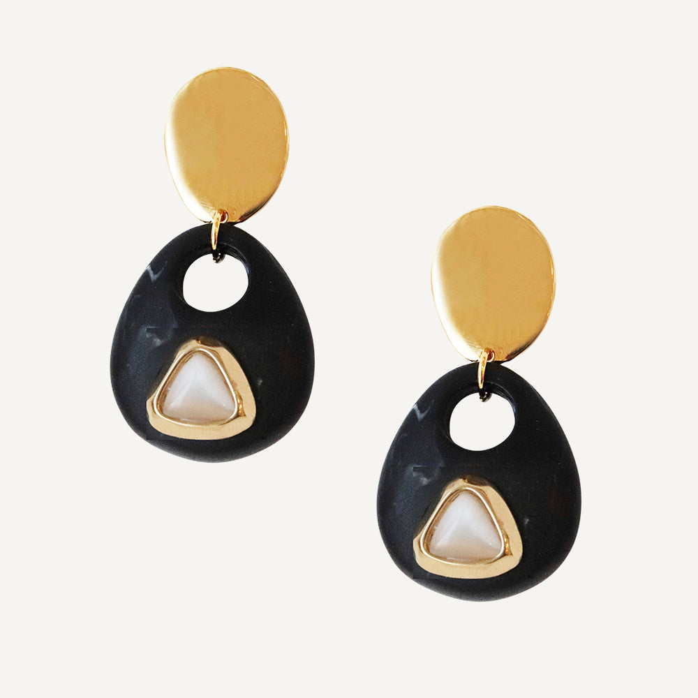 Pendientes negros con detalles dorados y perla en forma de triángulo, estilo moderno y elegante.