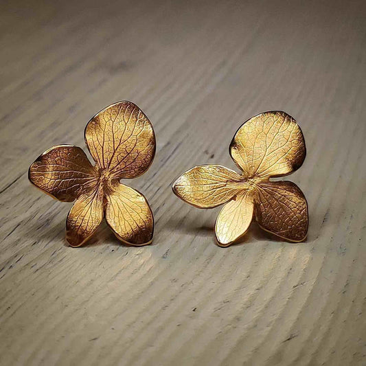 Pendientes de flores doradas en metal, diseño elegante y detallado, ideal para ocasiones especiales y uso diario.