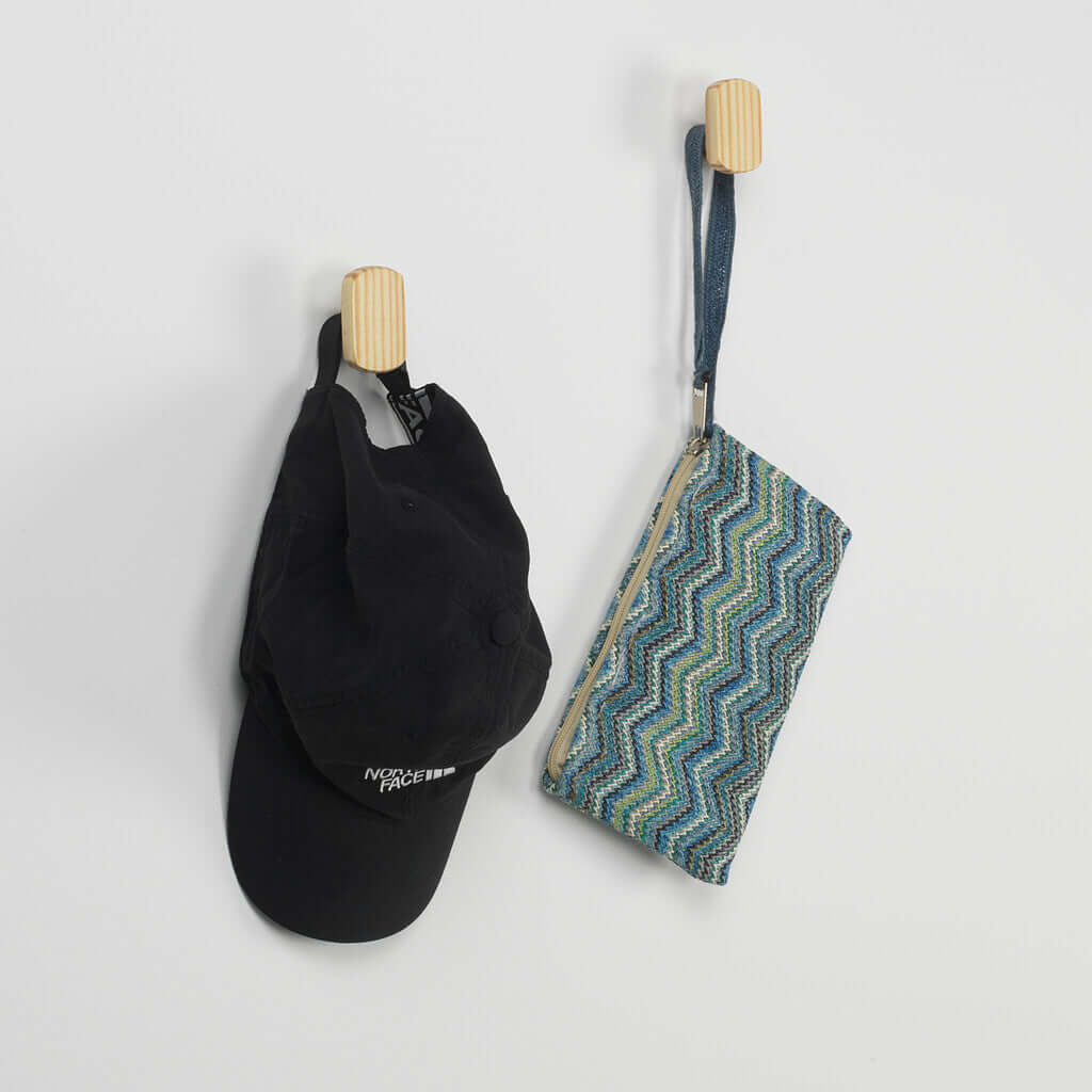 Colgadores de pared de madera maciza con gorra negra y bolsa de tela colorida colgados.
